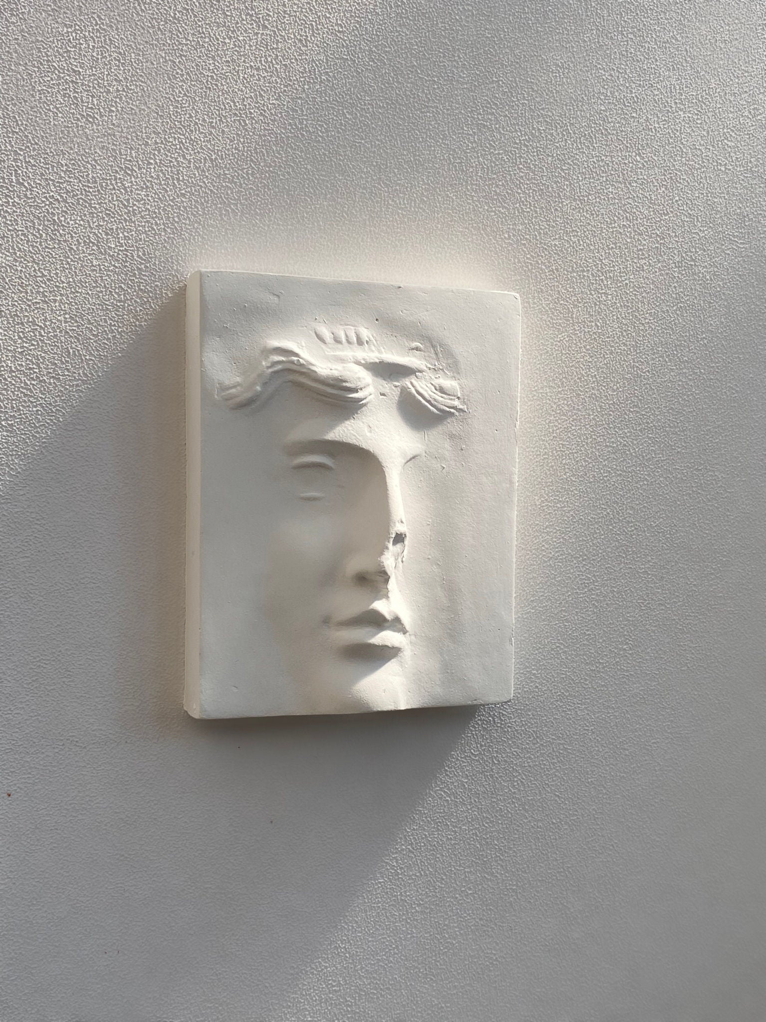 White plaster relief sculpture showing serene face in profile