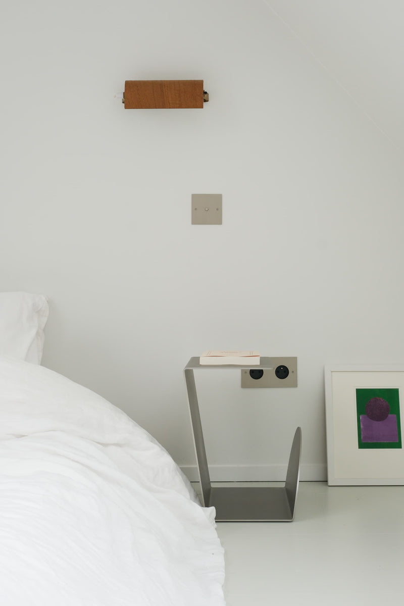 Side Table - 1.0 - Stainless Steel — angled view beside bed in minimalist bedroom