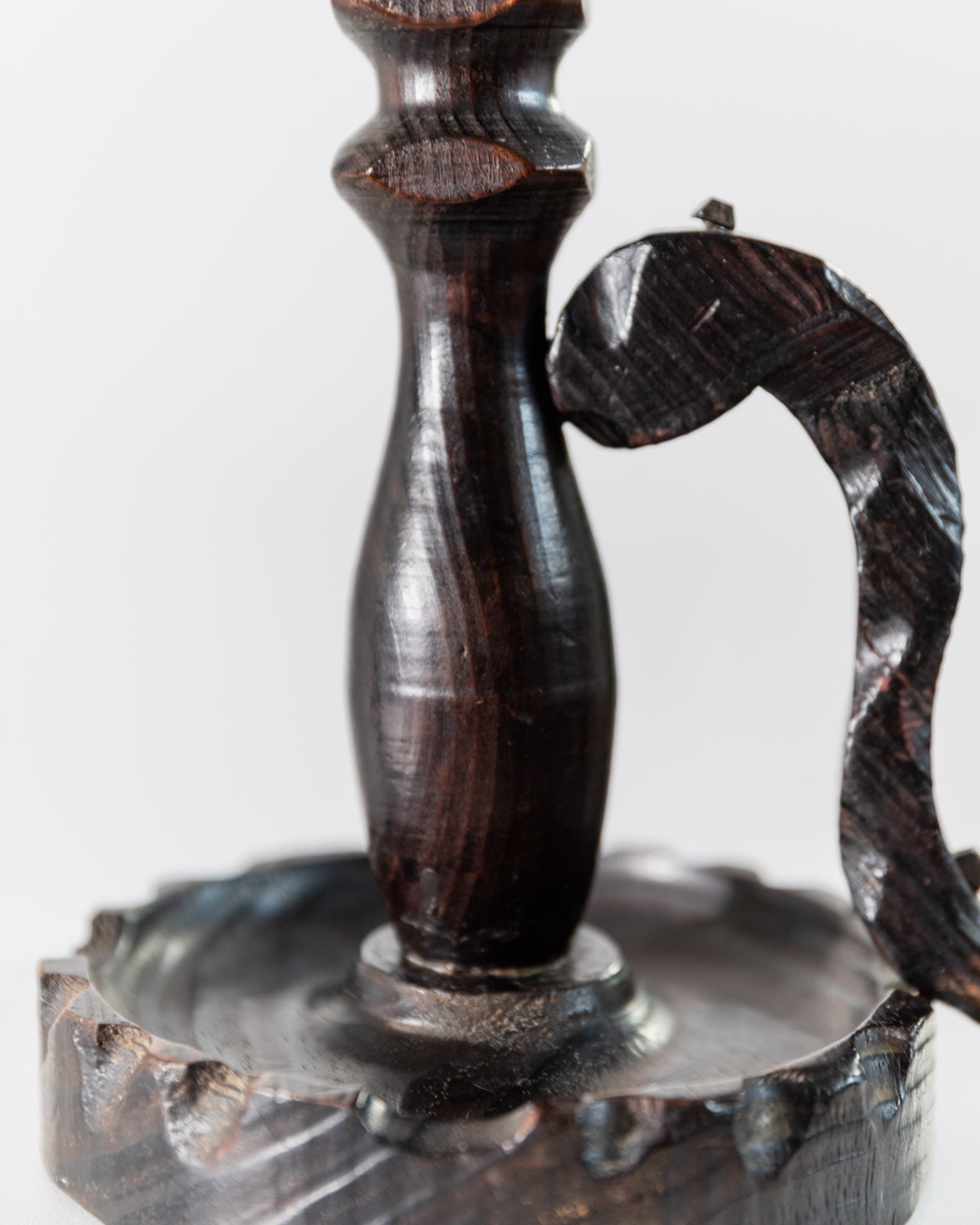 Close-up of the Bottega Jacobs 1960s Wooden Candleholder, handcarved in dark wood with a rounded base, tapered column, and curved handle, shown against a plain white background.