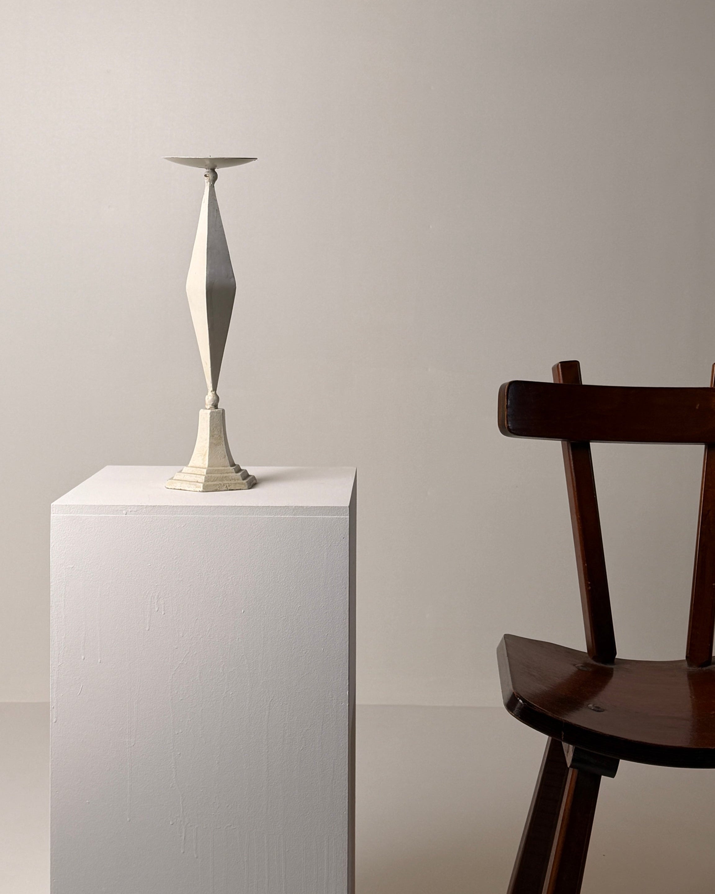 White-patinated Iron Candlestick, France, early 20th century — angled view on white pedestal