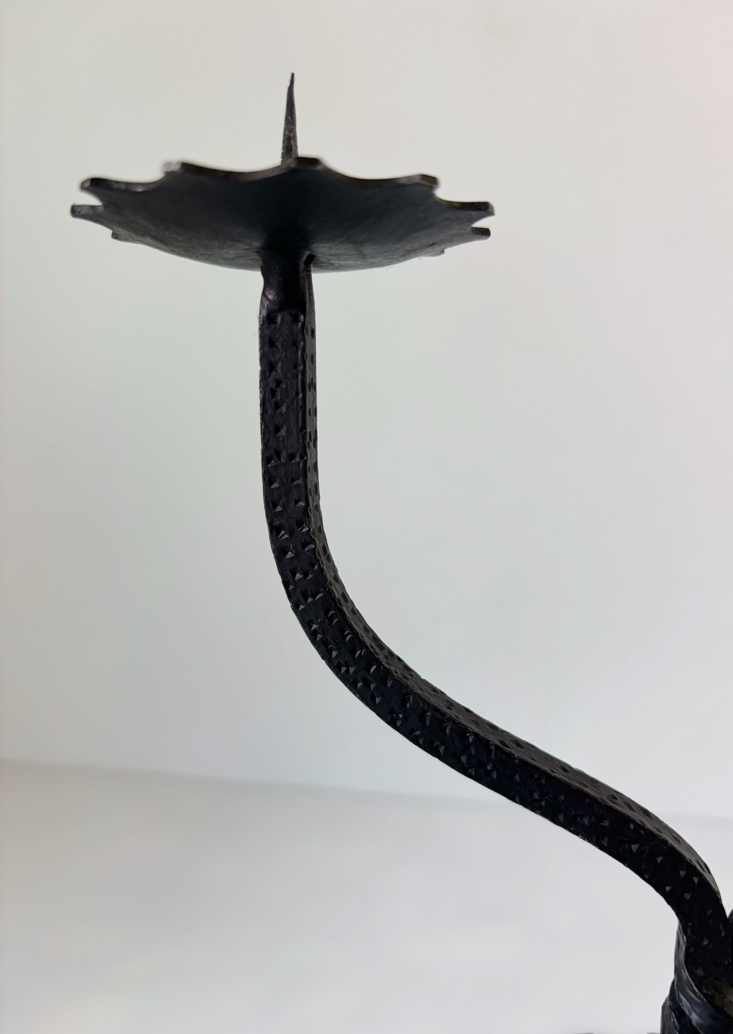 Sculptural black metal candleholder with curved serpentine stem