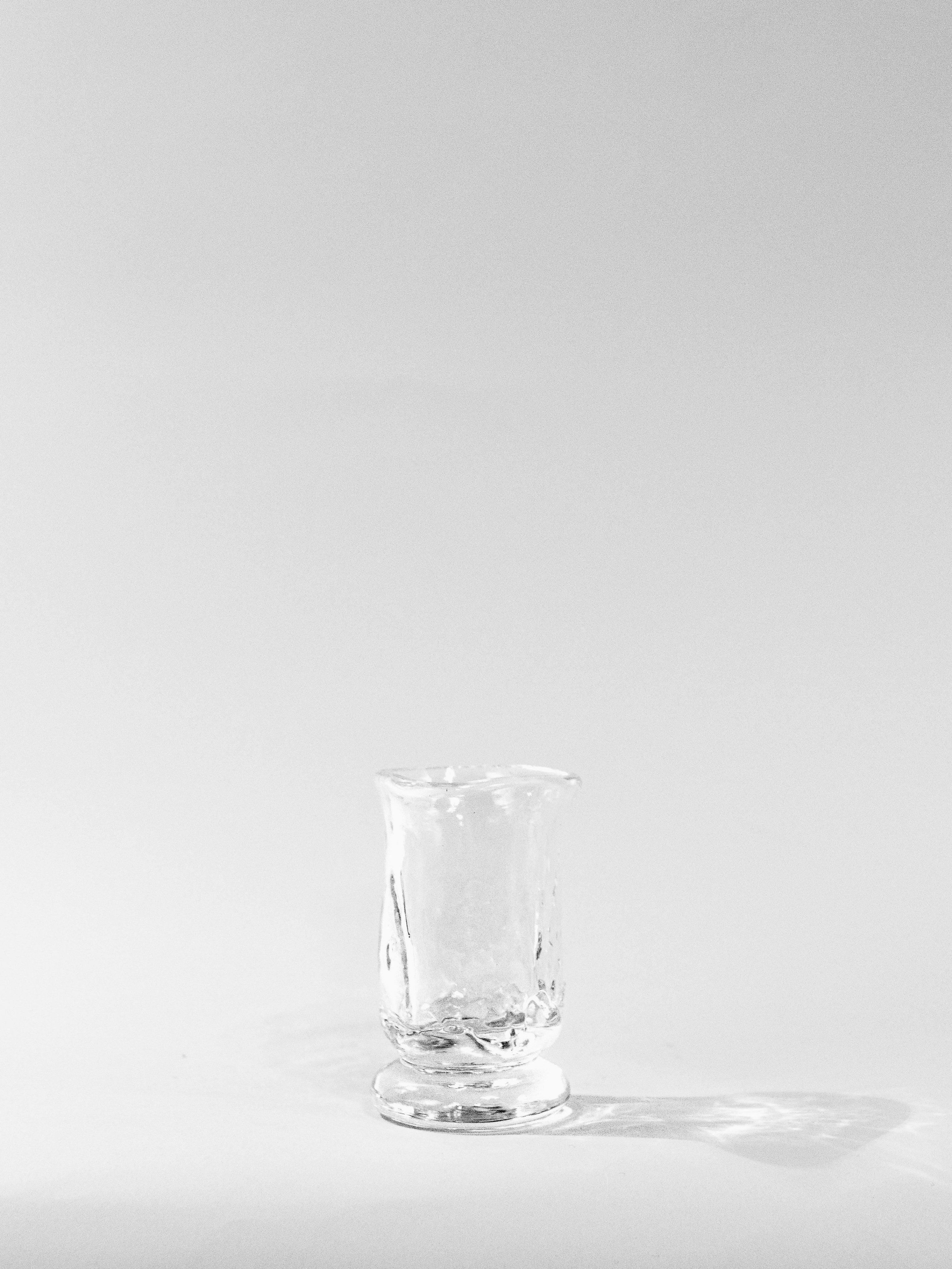 The Organic Shaped Table Glass by Szkło Studio sits empty on a white surface against a plain white background, casting a subtle shadow to the right.