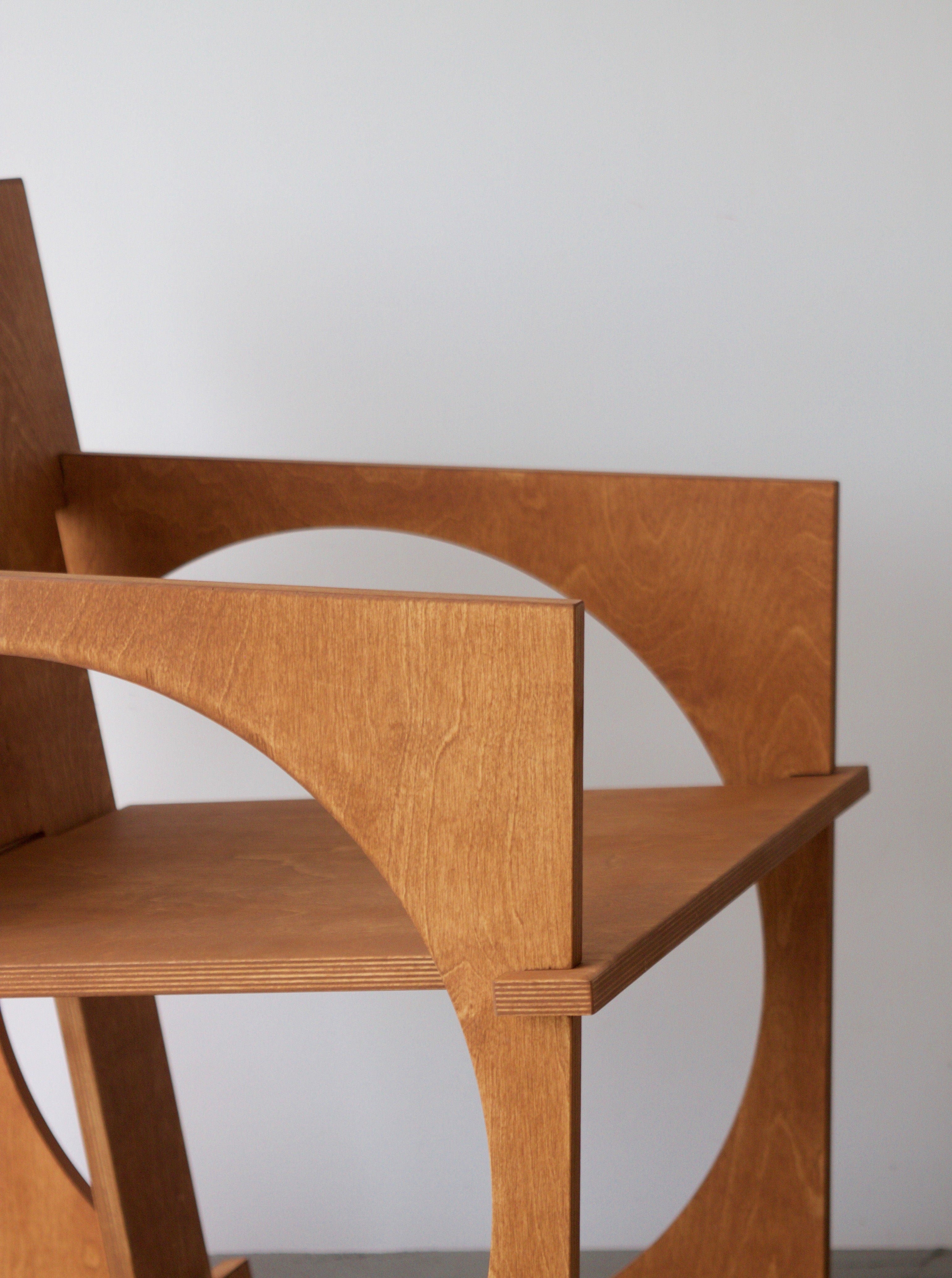 Close-up of a Sedia Tonda by Edoardo Lietti Studio with smooth, curved armrests and a minimalistic design, set against a plain, light-colored wall.