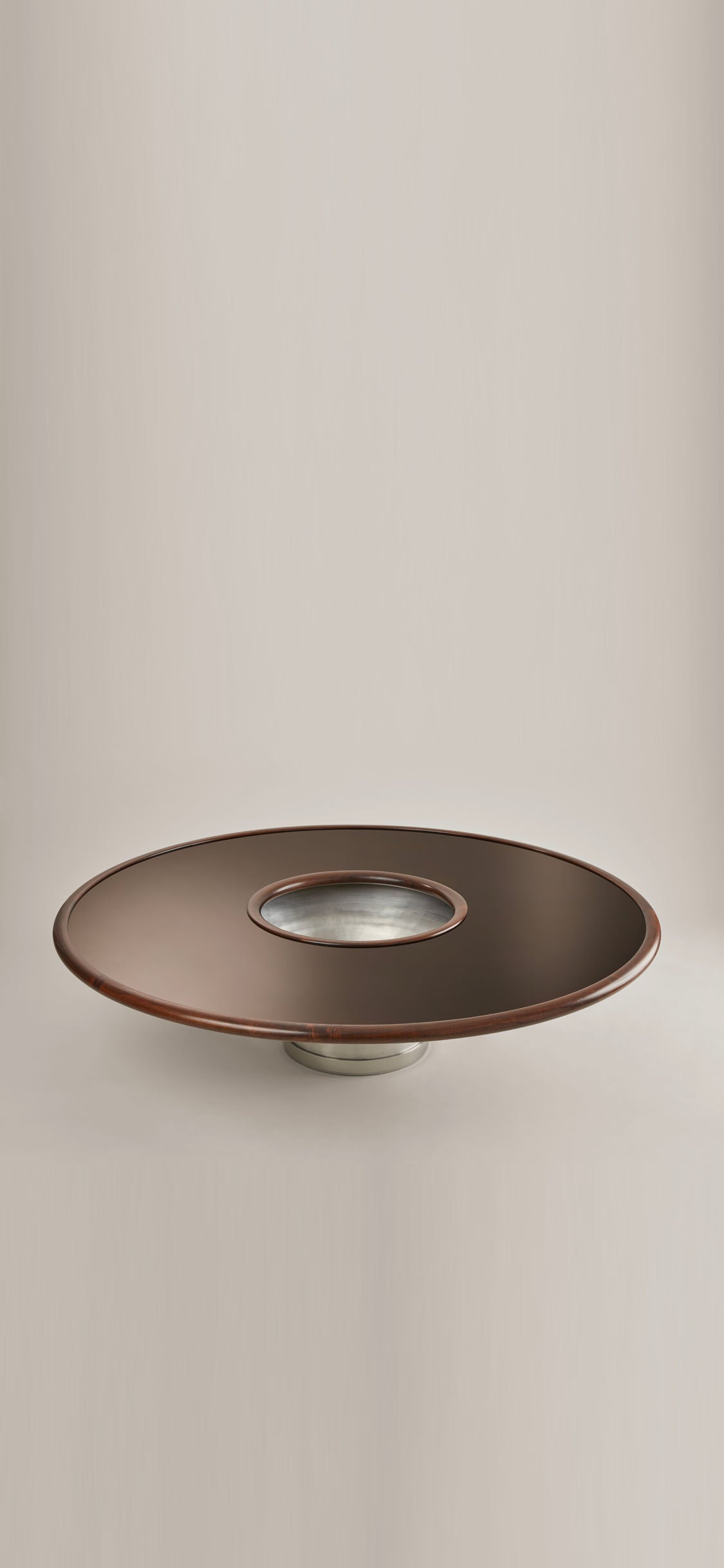 Experience the elegance of the Loulou by HAUVETTE & MADANI, a sleek, modern round table de salon featuring a dark brown bois laqué surface with a central aluminium repoussé accent, all set against a neutral background.