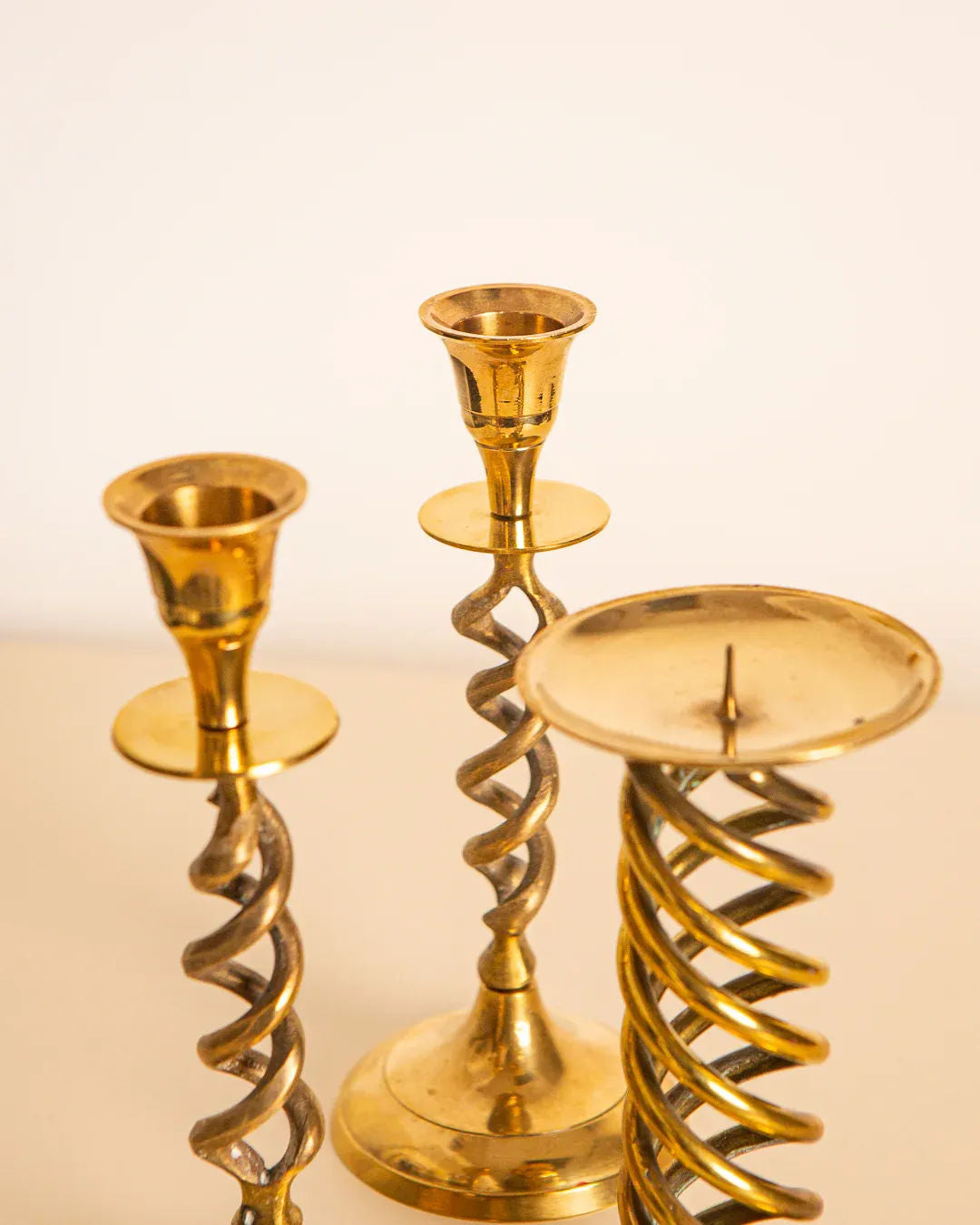 A set of 3 Treaptyque Italian 60's Gilded Metal Candleholders with spiral designs is displayed against a light background. The absence of candles emphasizes the intricate craftsmanship of the metalwork.