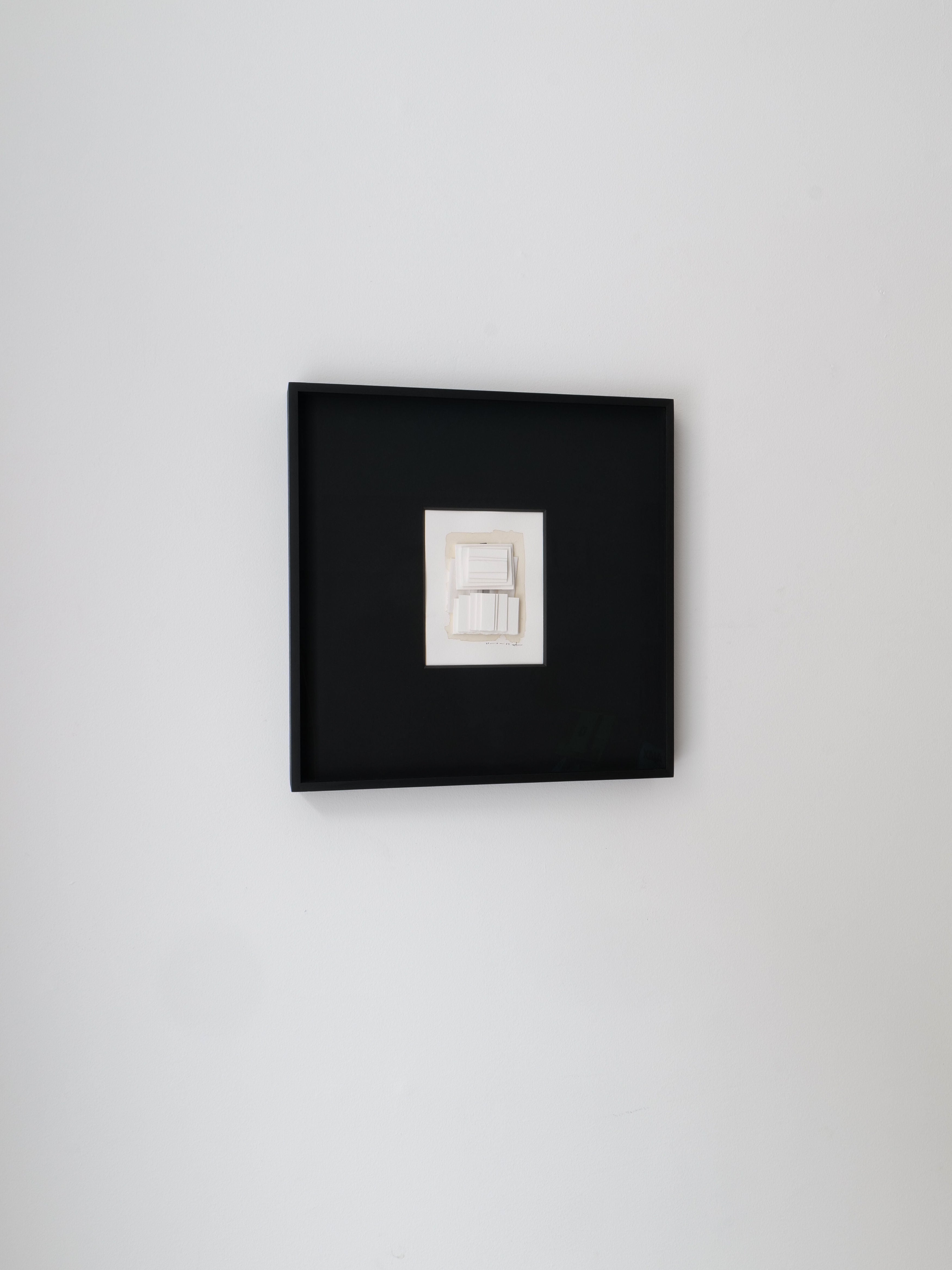 The minimalistic "Collage No.03 Rasmus Wingårdh" by Collection apart, an elegant mixed media piece with a simple line drawing and soft shading, is framed in dark wood and hangs on a white wall.