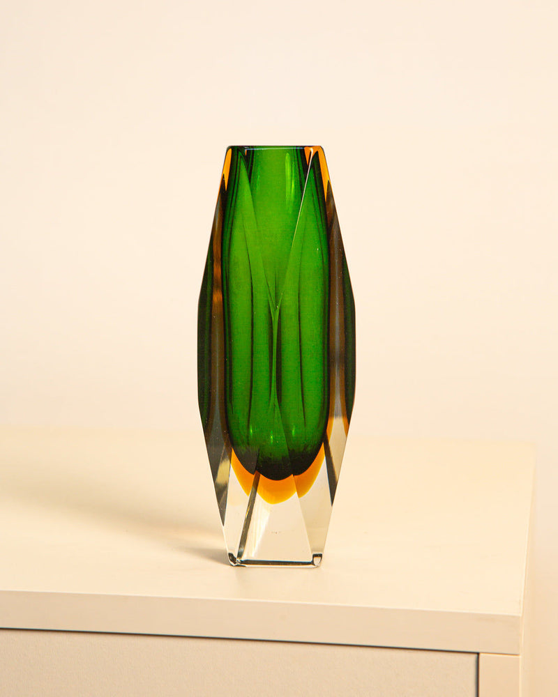 The Parrot-green "Diamond" Vase by Flavio Poli for Treaptyque, an Italian blown glass piece from the 80s with green and amber tones, is showcased on a white surface against a beige background.