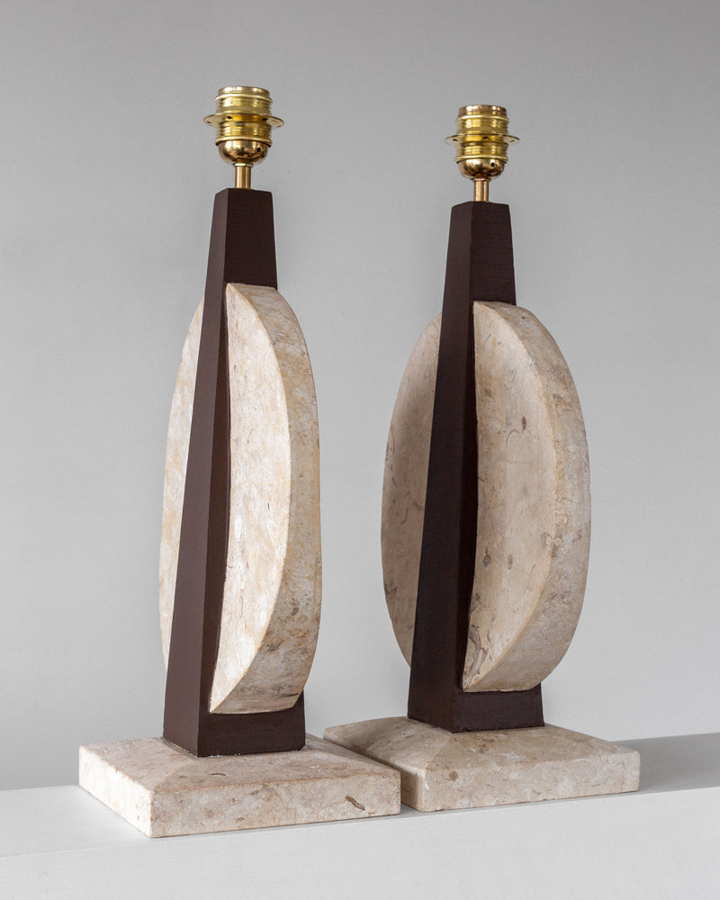 The Spigel Pair of Large Travertine Table Lamps from the 1970s features a shade-less geometric design with dark wood accents and stone-like materials on travertine bases, blending angular and circular elements for a vintage lighting charm.