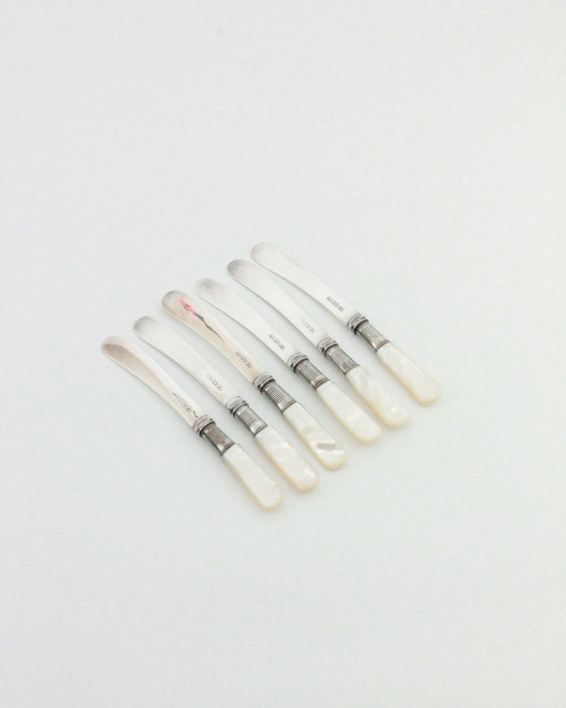 Six Boga Avante Shop Mother-of-pearl Butter Knives are arranged in a neat row on a plain white background.