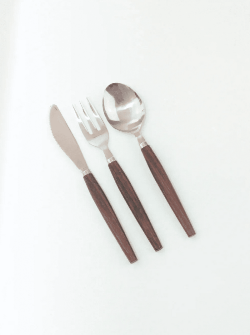 A set of three pieces of the Mid-Century Cutlery Set from the Boga Avante Shop on a white background, including a knife, fork, and spoon. Each piece features a polished stainless steel head paired with sleek teak handles.