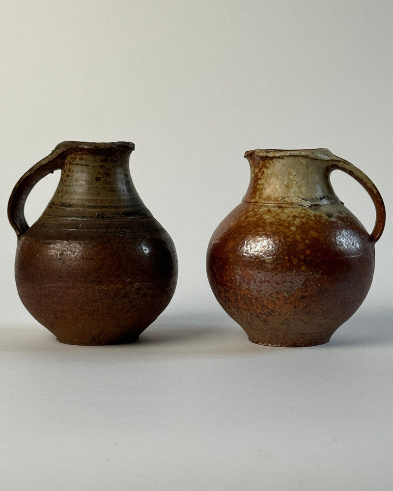 Two brown ceramic pitchers by Jacky Coville with glazed finish