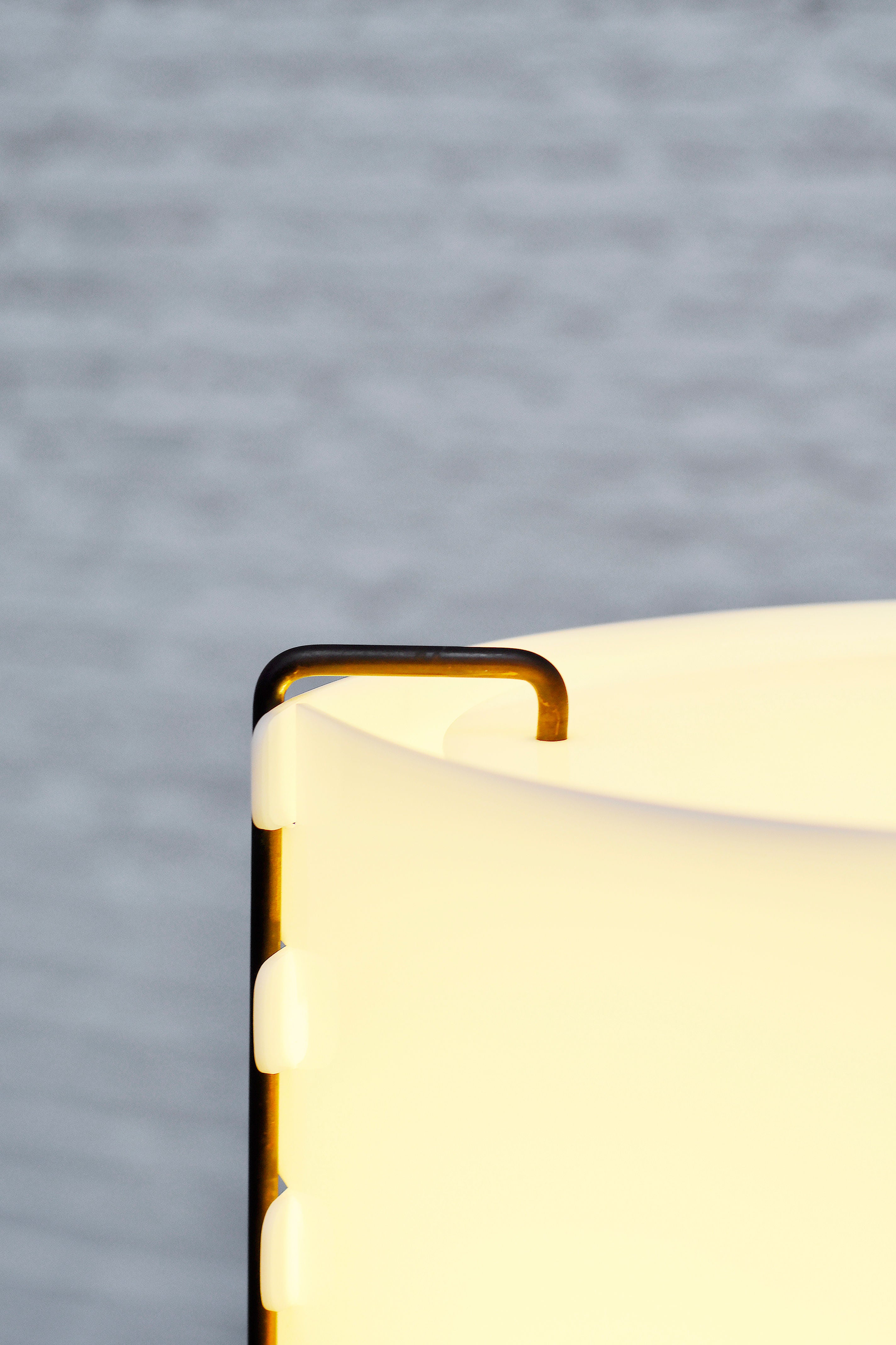 Close-up of the rare 'M8 Fanal' lamp by Joseph-André Motte for Huchers-Minvielle (1958), highlighting its curved metal frame and smooth, translucent white shade. The blurred background emphasizes Introverso's elegant French mid-century modern design.