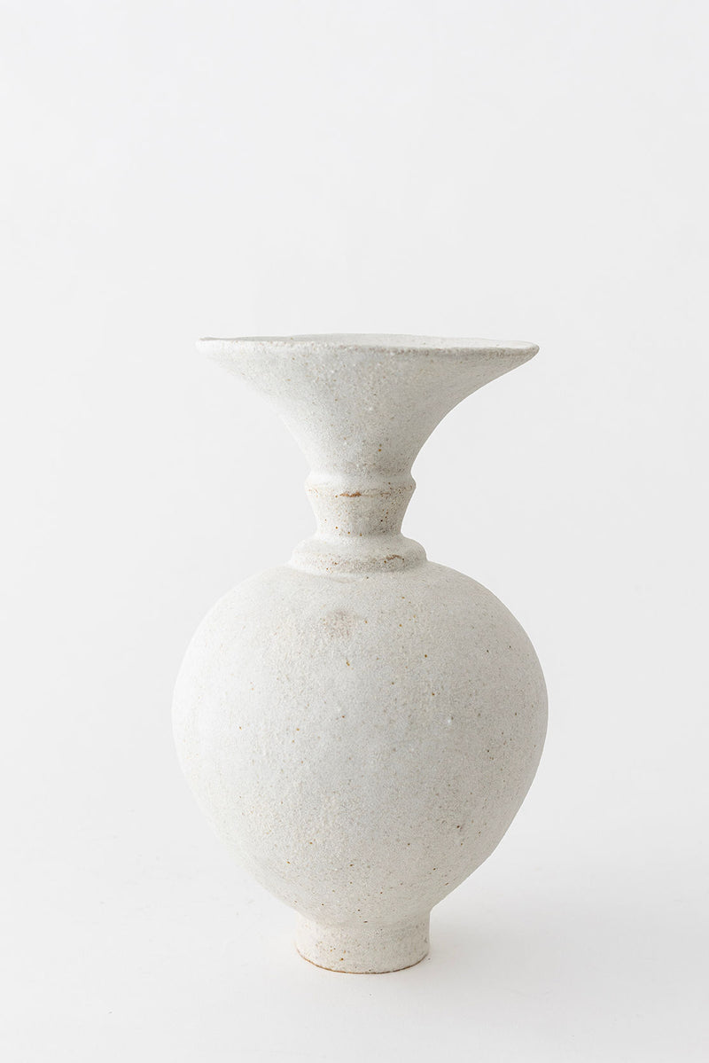 The Ánfora Blanco Hueso Vase by Canoa Lab is a light gray, textured ceramic piece featuring a round body, narrow neck, and flared rim, showcasing handmade Valencia craftsmanship against a plain white background.