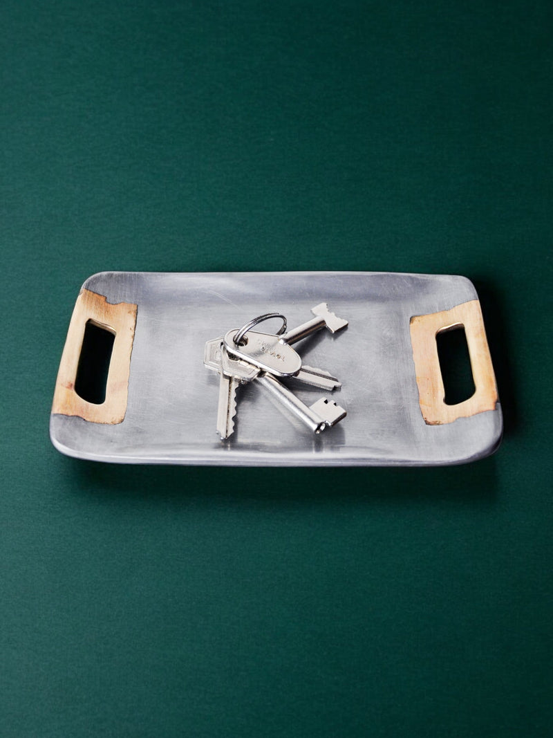 Brutalist aluminum vide-poches with keys on green surface