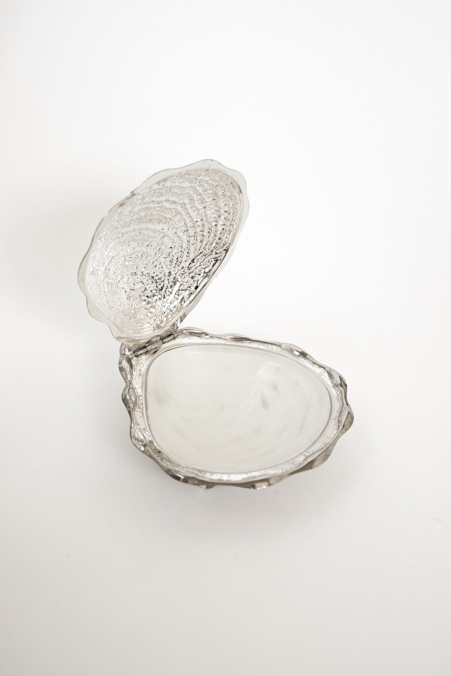 The Shell Butter Dish by septembre studios features a vintage metallic scallop shell design with a textured exterior, shown open on a white background to display its smooth, reflective interior.
