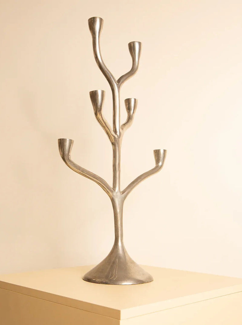 The Italian Candleholder 80s, crafted from cast aluminum and designed to resemble a tree with multiple branches, sits on a beige surface against a plain, light-colored background. This piece of exquisite Italian craftsmanship by Treaptyque features six curved arms, each ending with a holder for a single candle.
