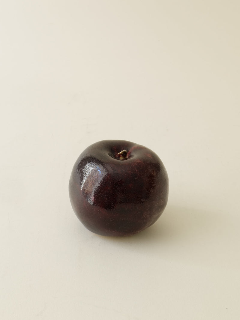 Dark burgundy ceramic apple sculpture with glossy finish