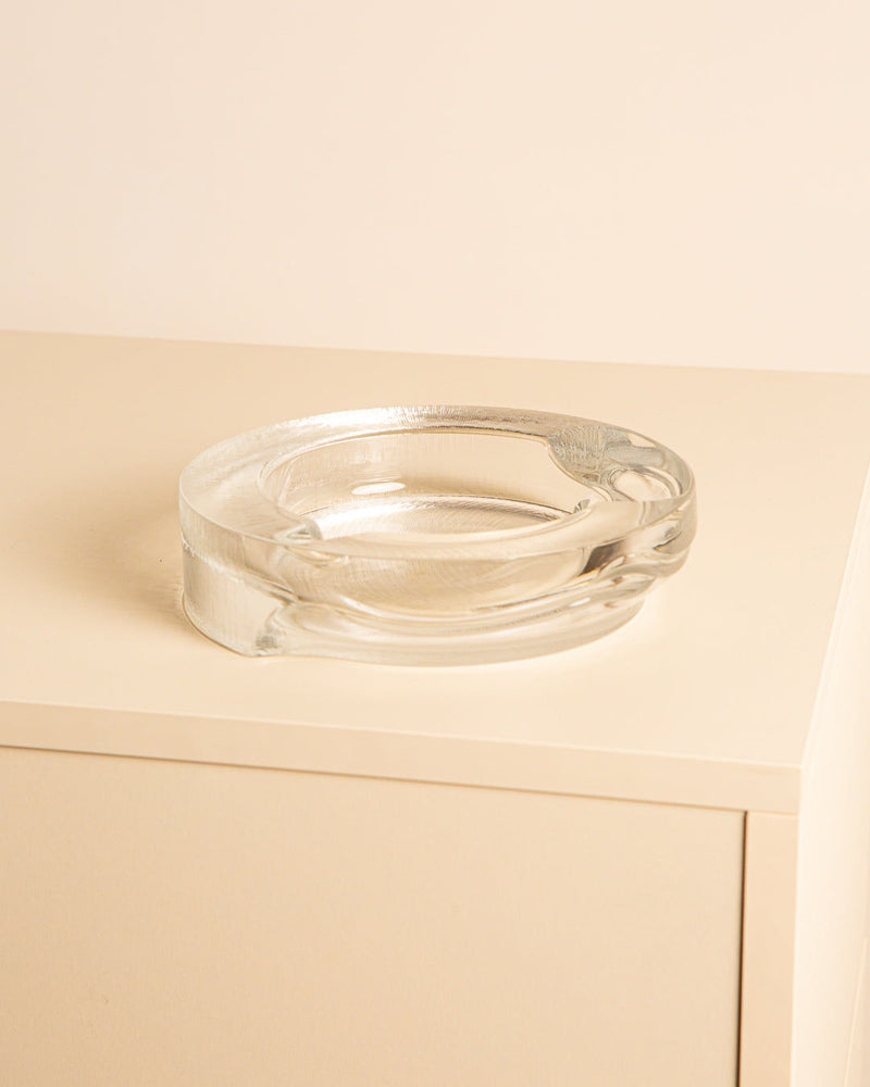 Clear glass ashtray with curved design on wooden surface detail