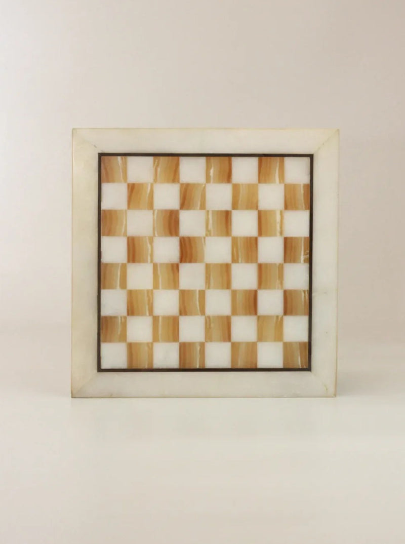 The Boga Avante Shop Vintage Marble Chessboard, crafted from marble stone, showcases a square design with alternating light brown and white squares. The chessboard is bordered by a light grey marble frame and is situated on a neutral background.