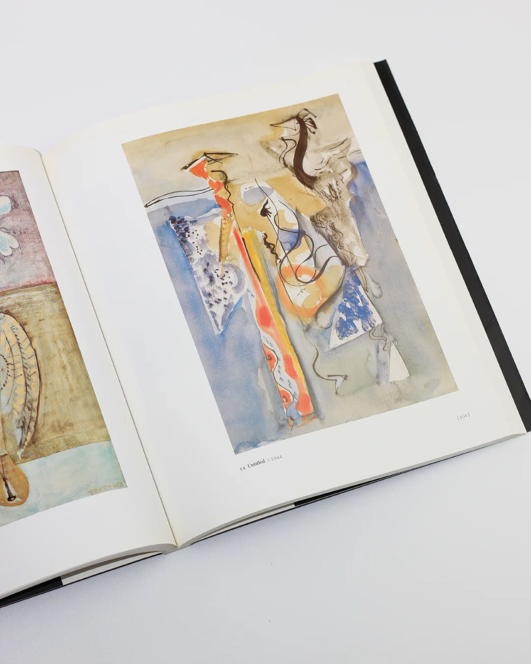 The Mark Rothko Book from Boga Avante Shop showcases abstract paintings with fluid shapes and muted colors, including a central piece inspired by Abstract Expressionism, featuring dynamic lines in orange, blue, and gray against a light background.