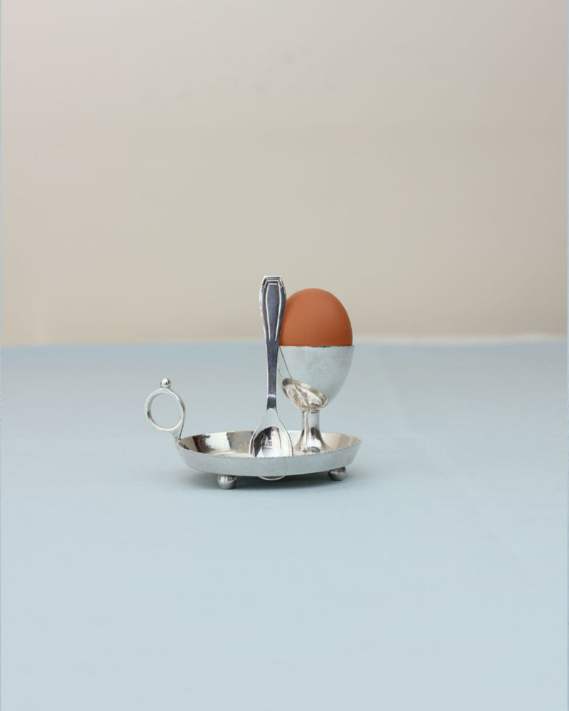 Silver egg cup with spoon on oval tray, brown egg displayed