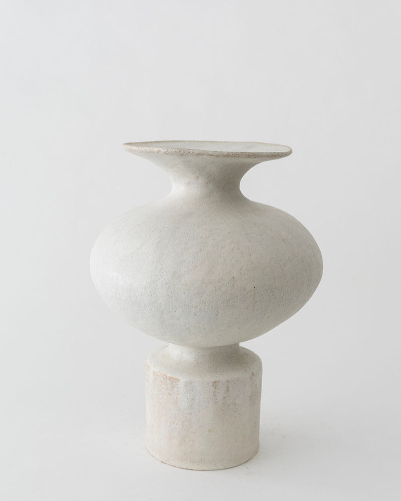 The Isolated n.11 Perla Vase by Canoa Lab is a minimalist off-white ceramic piece with a wide flat rim, round body, and cylindrical base, shown against a plain light background.
