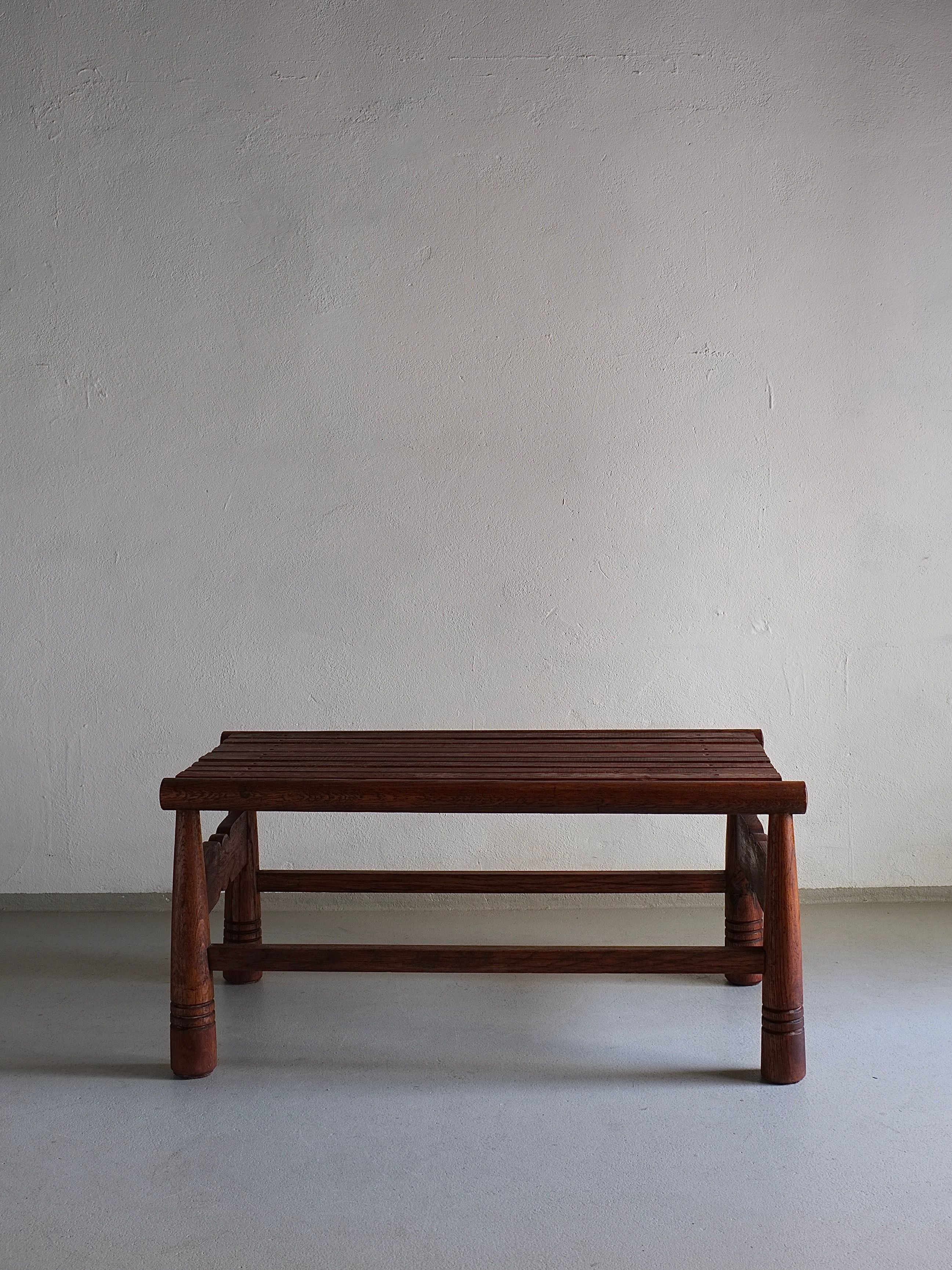 A Carved Dark Oak Bench by Veter Vintage, crafted in France in the 1960s, stands against a plain, light-colored wall. The bench's minimalist design features a flat seat and four sturdy legs with crossbars for added support. The rich brown wood grain is visible, adding a touch of natural warmth to this vintage piece.