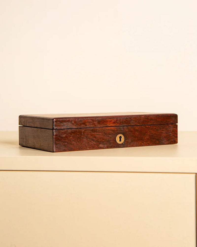 The Treaptyque Italian Rosewood Box 60s, a handcrafted rectangular storage box with a brass keyhole, is displayed on a light surface against a plain beige background.