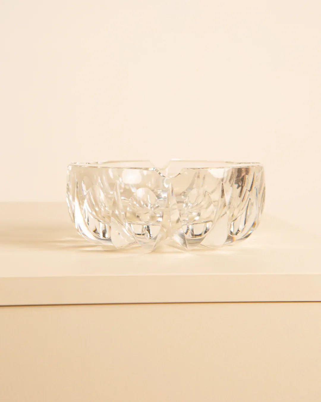 Saint-Louis “Ambassadeur” D120 Ashtray from the 1970s, by Treaptyque, in clear crystal with intricate leaf-like patterns, placed on a light-colored surface against a beige background.