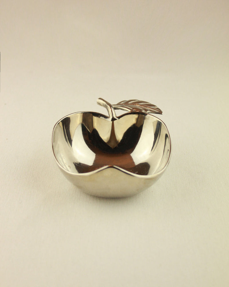 The Decorative Apple Shaped Dish by Boga Avante Shop is a small, shiny silver bowl with a metallic stem and leaf detail, ideal as a serving bowl, shown on a plain light background.