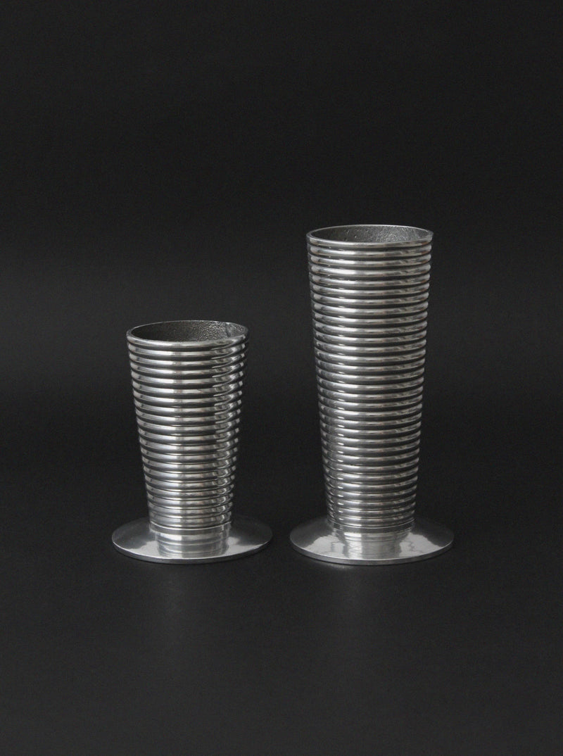 Two ribbed aluminum vases in different heights on dark background