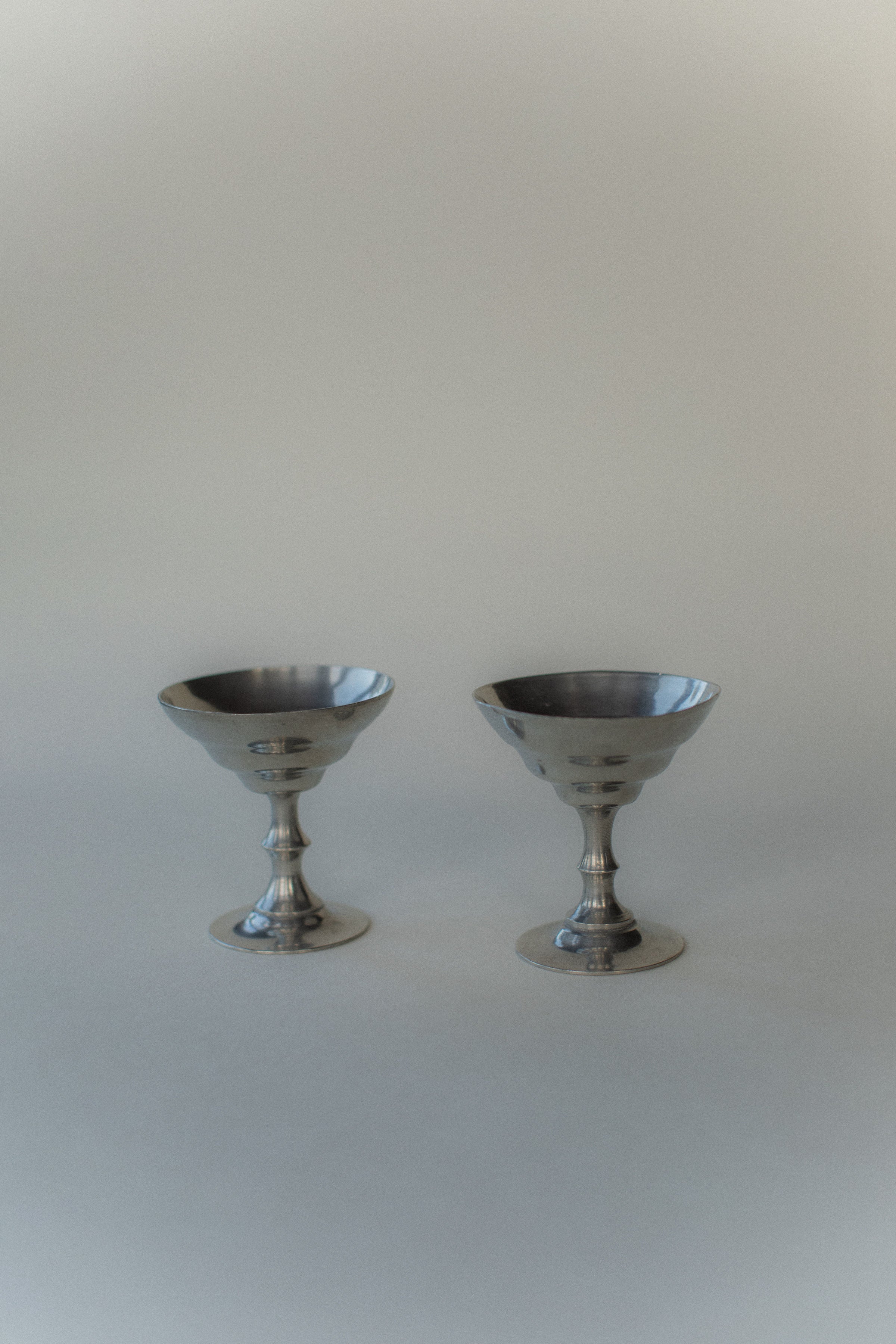 Two Ice Cream Cups by Out For Lunch, featuring broad rims and narrow stems in a vintage style, are elegantly positioned side by side against a soft, neutral background for a minimalist composition.