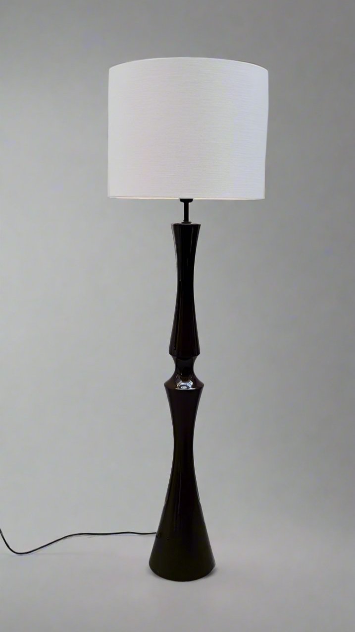 LA NOUVELLE GALERIE's Ceramic Floor Lamp by Cari Zalloni is a sleek, modern design featuring a dark, glossy ceramic column base that narrows in the middle and supports a large, white cylindrical lampshade. Reminiscent of 70's French luminaires by Zalloni, the lamp stands on a light grey background with a power cord extending from its base.