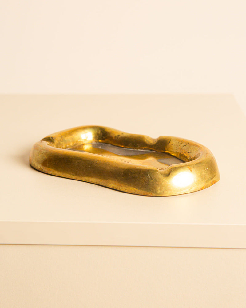 Golden brass brutalist ashtray with sculptural curved form