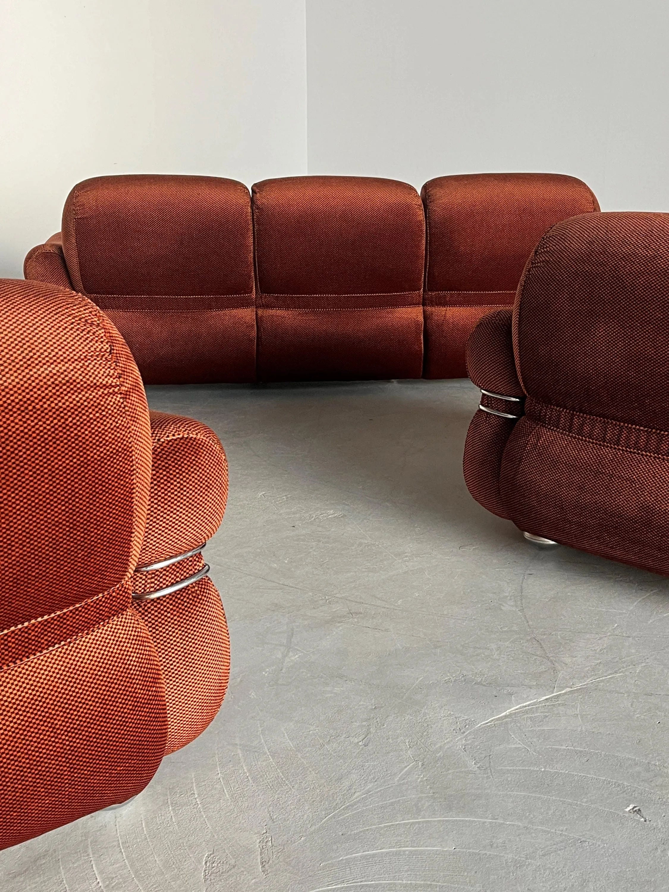 In a minimalist room with light gray flooring and white walls, three Italian Space Age Seating Sets by Cherry Cargo, featuring rust-colored checkered upholstery from the 1970s, create a modern and cozy atmosphere.