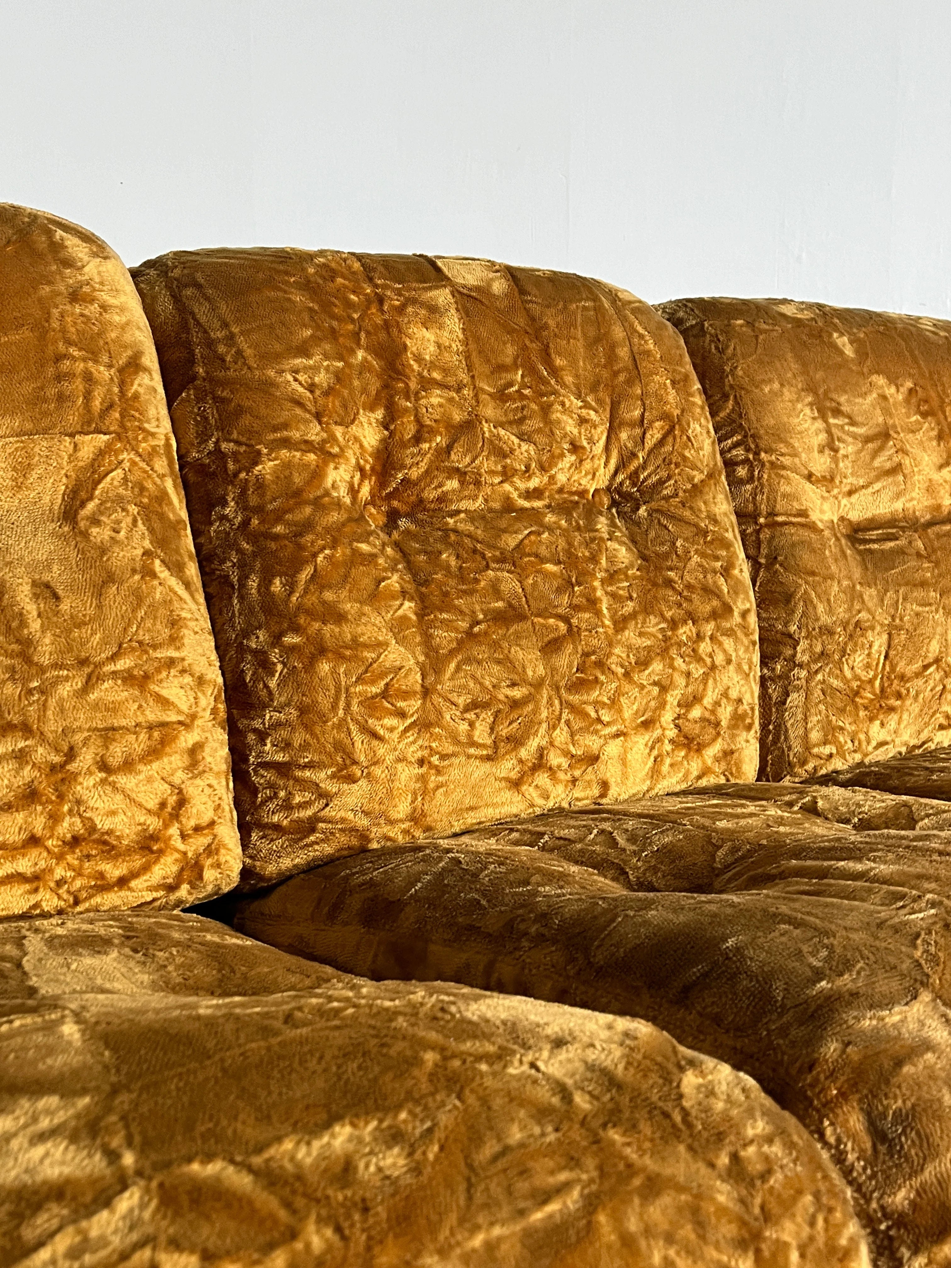 The Cherry Cargo Adriano Piazzesi 'Okay' Sofa Seating Set from the 1970s features golden brown, textured ochre velvet, creating a crumpled look for depth and warmth reminiscent of Mid-Century design, set against a plain white background.