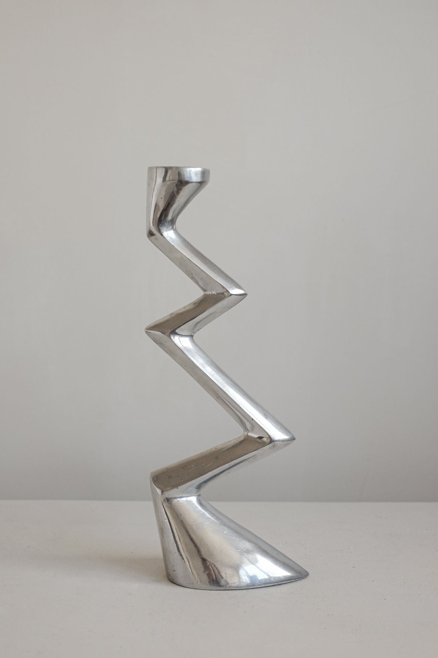 The Matthew Hilton ZigZag Candle Holder Large by septembre studios features a tall, modern angular silhouette, standing on a plain surface against a neutral background—ideal for contemporary interiors.