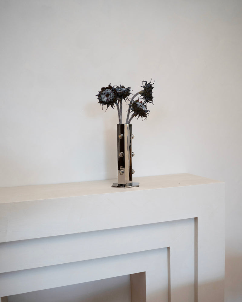 Titanium vase with dried sunflowers on minimalist white console