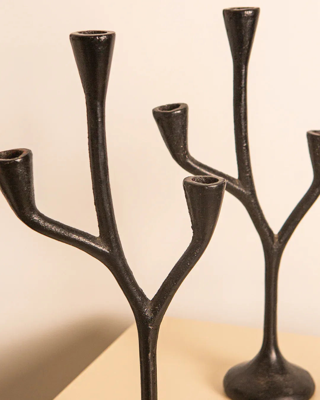 A set of three 'Arbre' candleholders from Treaptyque, made of black cast aluminium, adorn a light surface. Their tree-like design with multiple branches for candles highlights their artistic and minimalist style, showcasing Italian craftsmanship from the 80s.