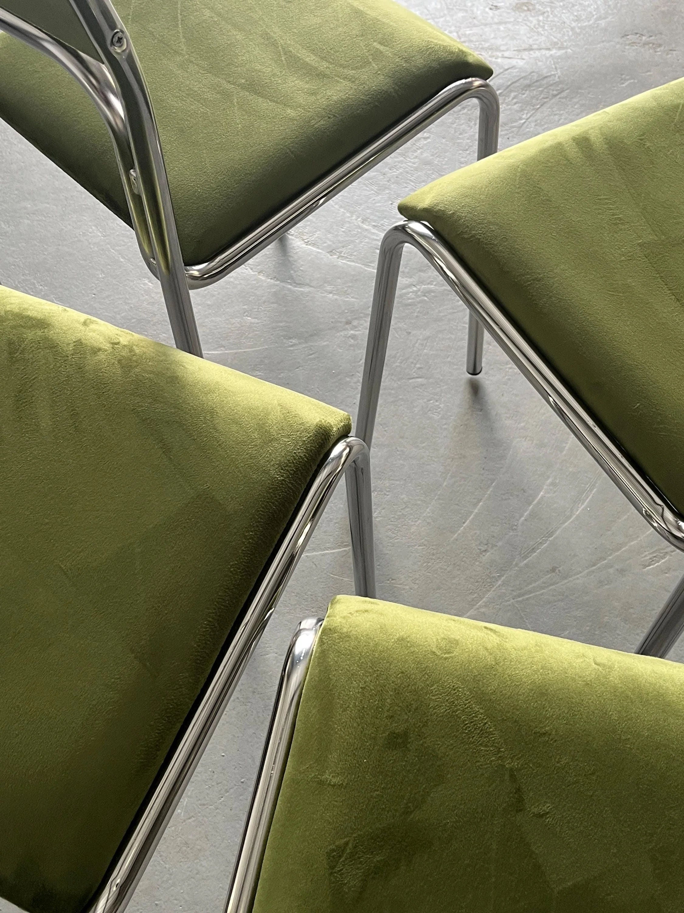 On a light gray floor, six green velvet chairs with chrome frames from Cherry Cargo embrace Bauhaus design. Featuring plush upholstery and tubular chrome legs, these chairs boast an Italian modernist flair.