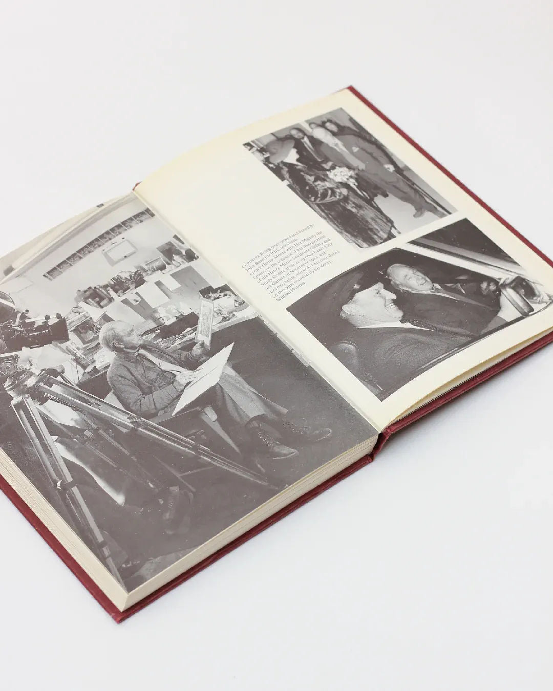 An open copy of "Henry Moore, An Illustrated Biography" by Boga Avante Shop featuring black and white photographs. On the left page, there's an image of a person drawing, while the right page displays people engaged in conversation and a man playing the violin, capturing the essence of modern sculpture.