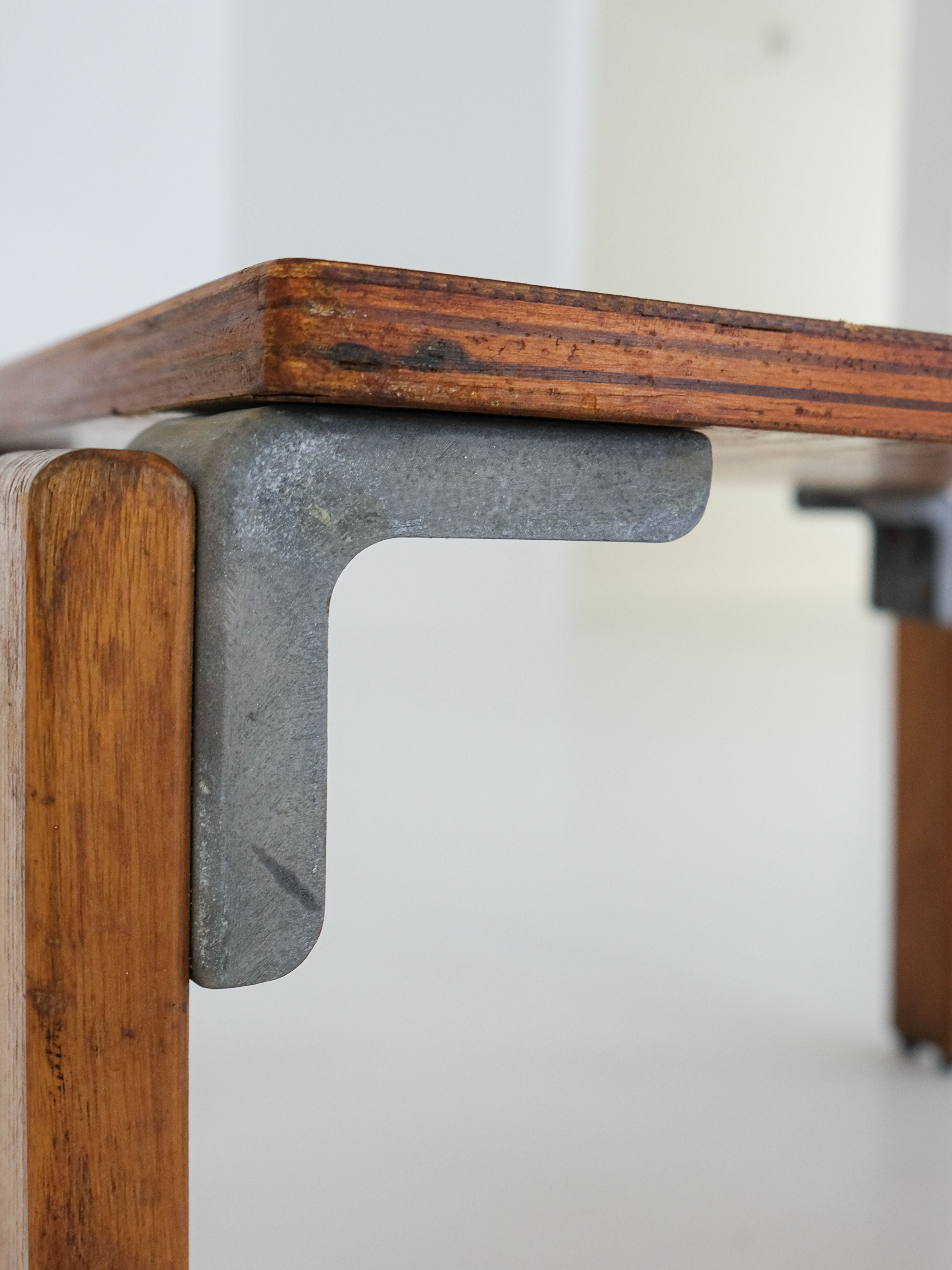 The Coffee Table by George Candilis and Anja Blomstedt (antibeige, 1970s) features a brown oak plywood top with a silver-gray metal bracket. Its vintage design is highlighted by a contrasting finish against a softly blurred background, capturing the era's charm.