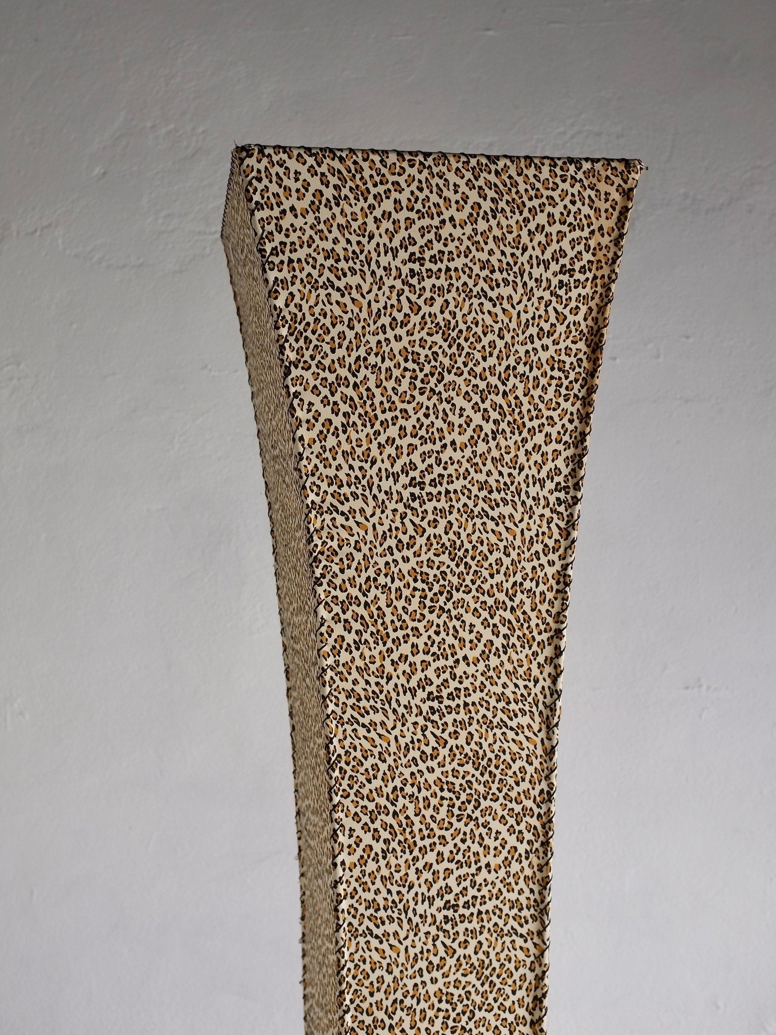 The Leopard Print Floor Lamp by Veter Vintage (1980s) stands tall and curved with a leopard print design against a plain light gray wall.