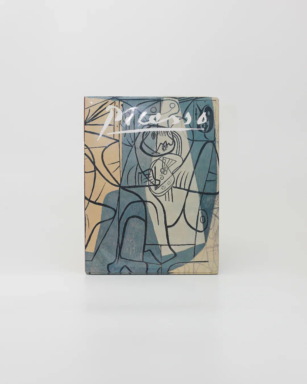 The Picasso by Gabriel Potter Vintage Art Book from Boga Avante Shop showcases a modern art piece in the cubist style, characterized by abstract forms and overlapping lines in blue, beige, and black tones. The artwork embodies the influence of Spanish artists such as Picasso, featuring geometric shapes and human-like figures that create depth against a plain white background.