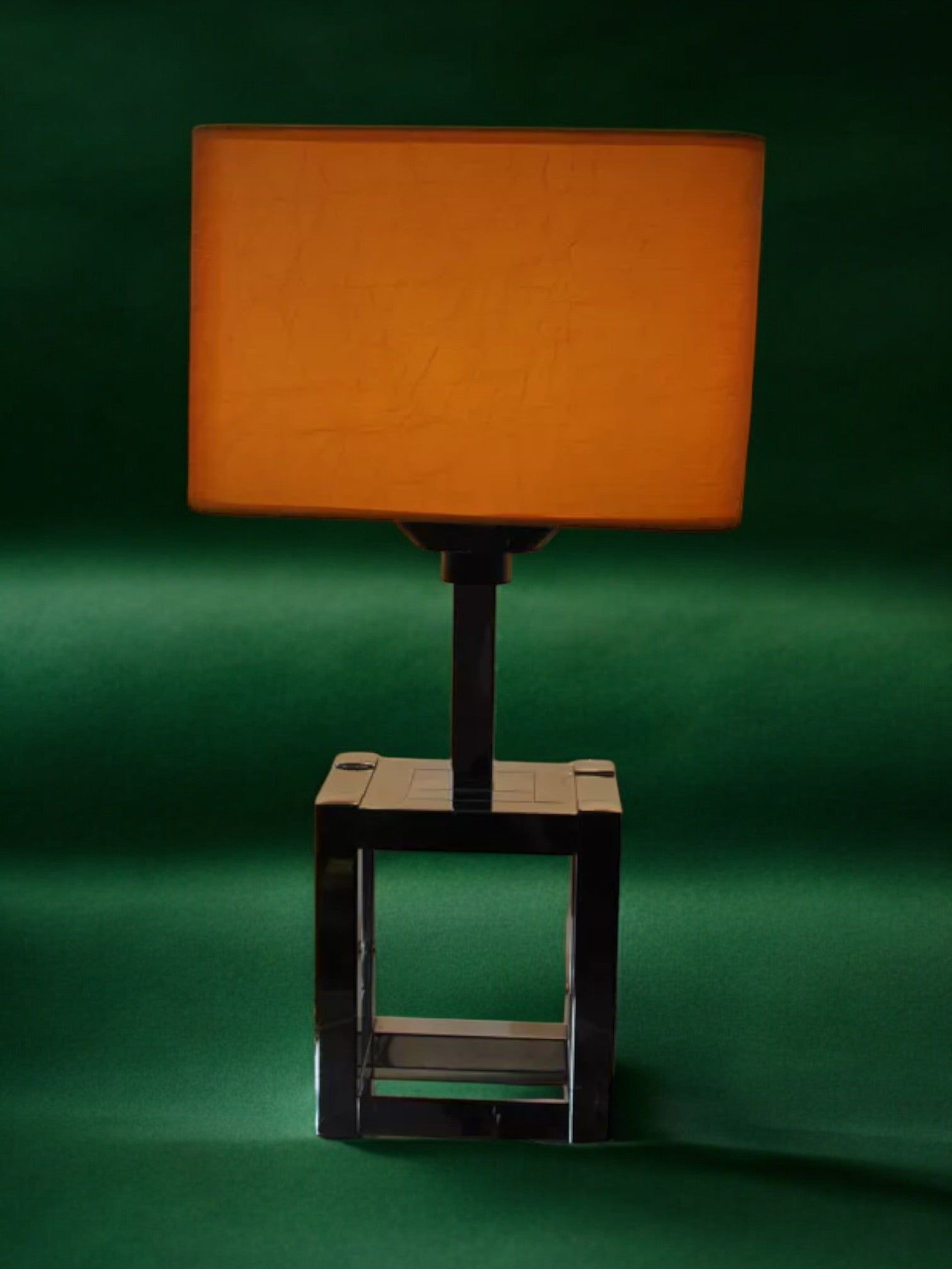 BD Lumica Cubic Table Lamp by Malamar Studio, Italy 1970, featuring a rectangular orange shade and chromed cubic base, set against a solid dark green background.