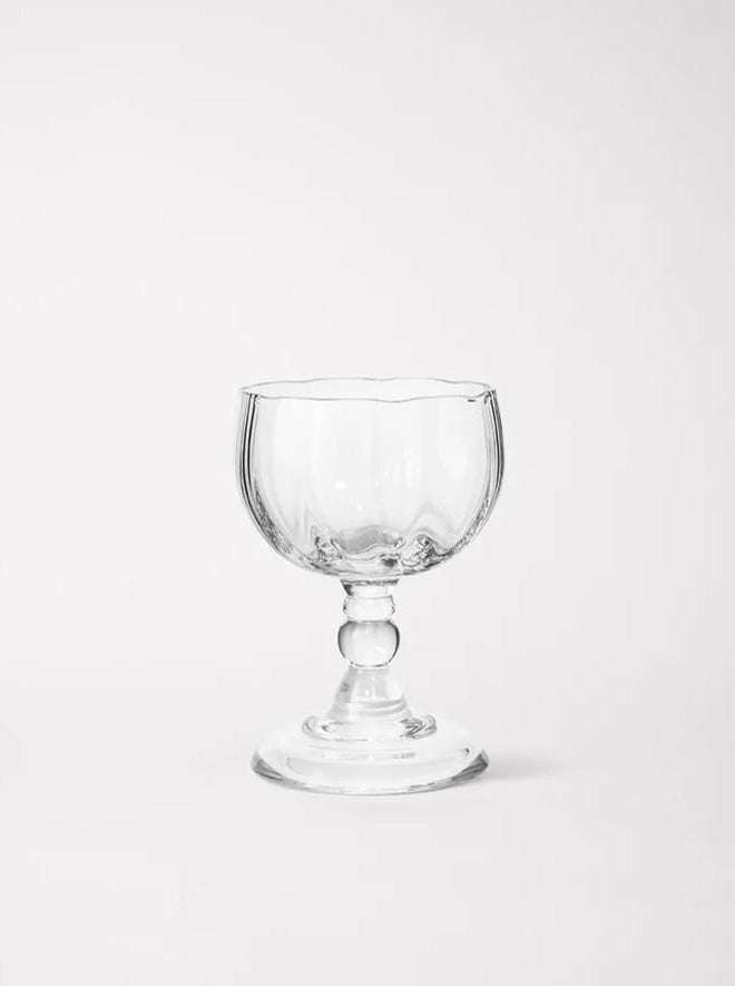 An empty, clear mouth-blown glass Alban Wine Glass Small - Set of Four goblet with an ornate design, including a stem with spherical details, against a plain white background by Akua Objects.