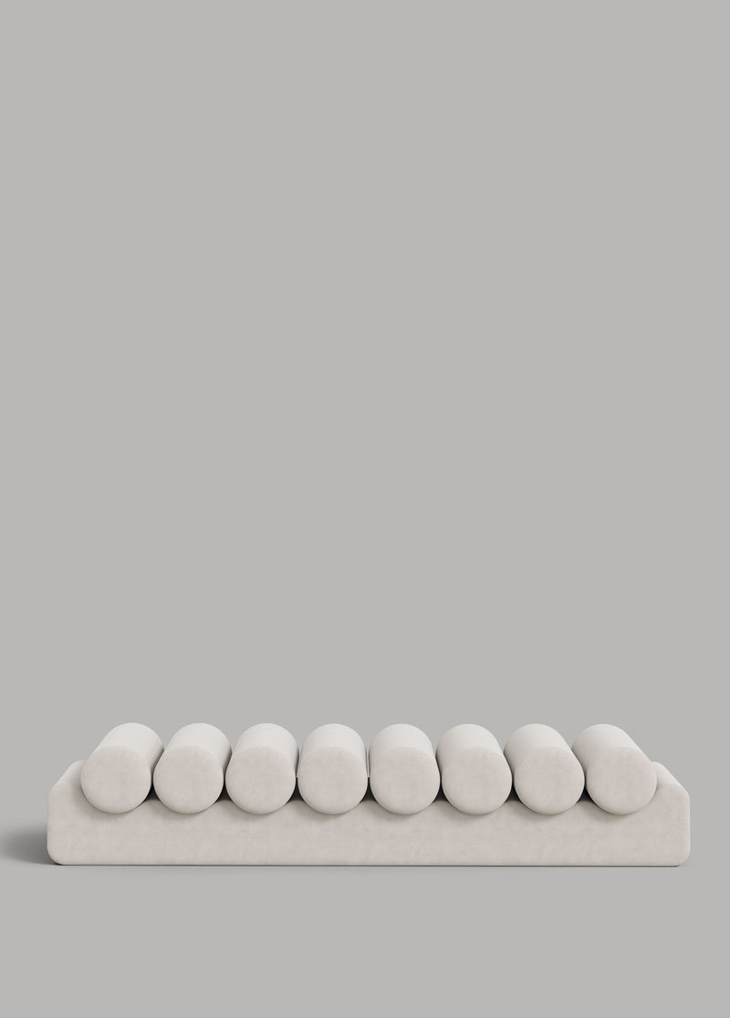 White velvet daybed with eight rounded cushions on platform base