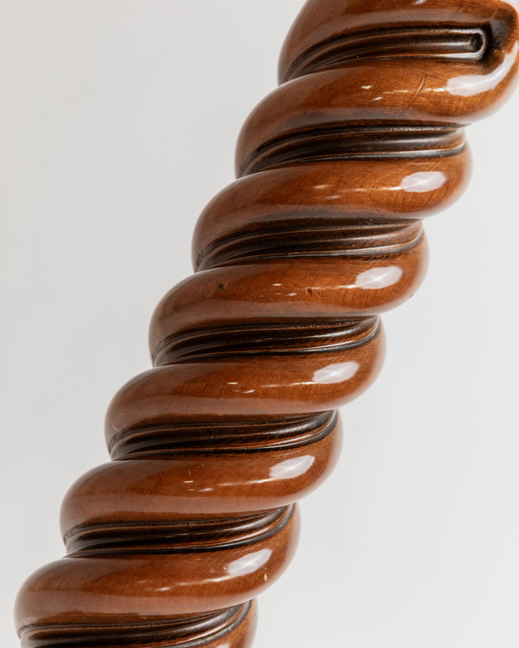 A close-up of the Bottega Jacobs Wooden Stand from Italy in the 1960s shows its solid wood spiral spindle with a glossy finish, featuring smooth, intertwined curves and polished brown tones with darker accents, reminiscent of a vintage wooden flower stand.