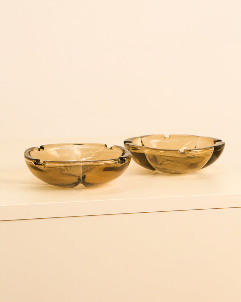 Two amber glass Italian ashtrays from the 1980s on beige surface
