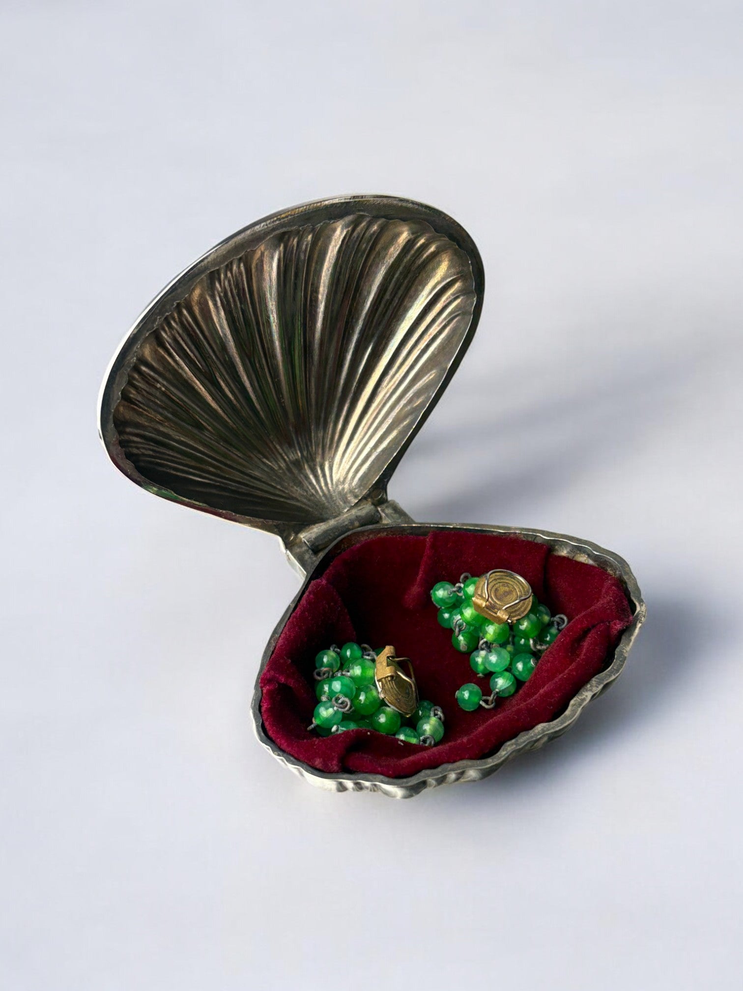 Silver plated shell jewelry box open revealing green earrings